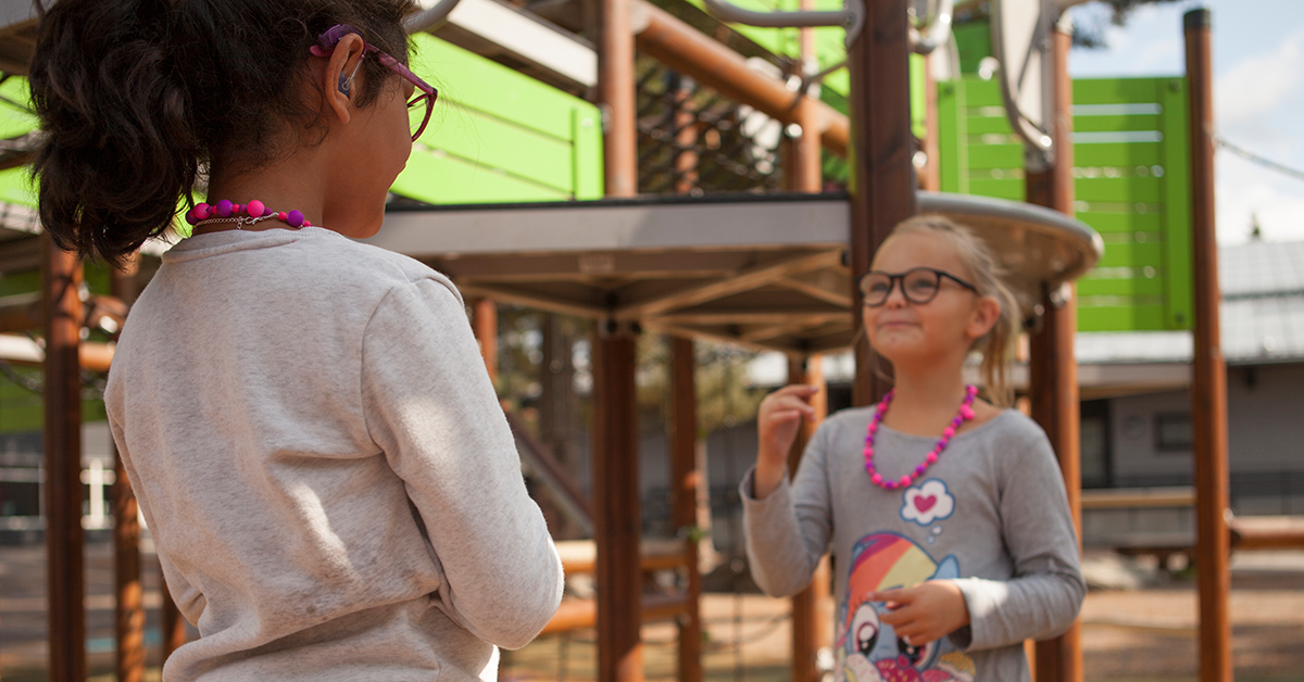 To barn som snakker tegnspråk på en lekeplass