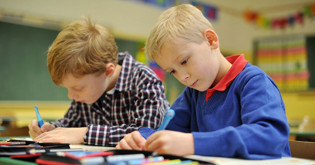 To gutter som sitter ved en skolepult